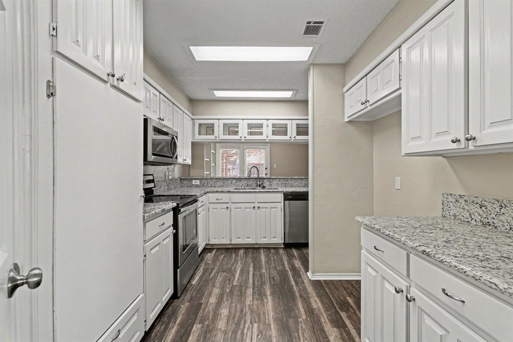 124 Summit Cove Trophy Club, TX 76262 - Photo 8 of 23 a kitchen with a sink dishwasher stove and white cabinets with wooden floor