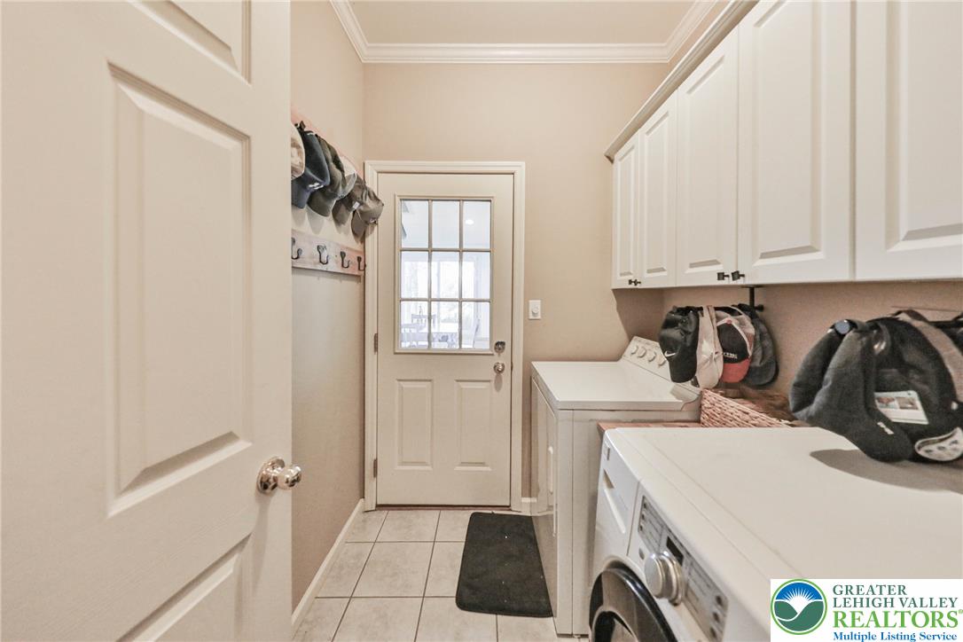 63 Long Road Lenhartsville, PA 19534 - Photo 56 of 100 White cabinetry, ceramic tile flooring, and classic crown molding details complete this functional utility space.