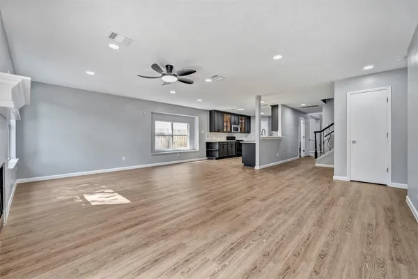 a view of an empty room with a window and wooden floor
