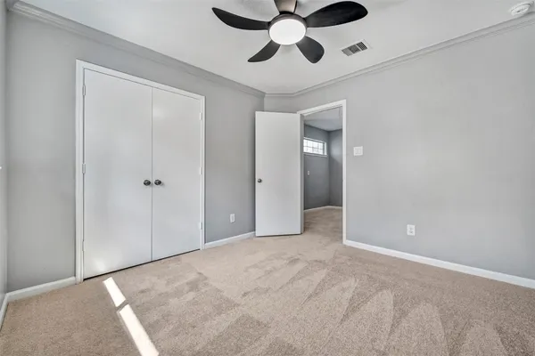 a view of an empty room and chandelier fan