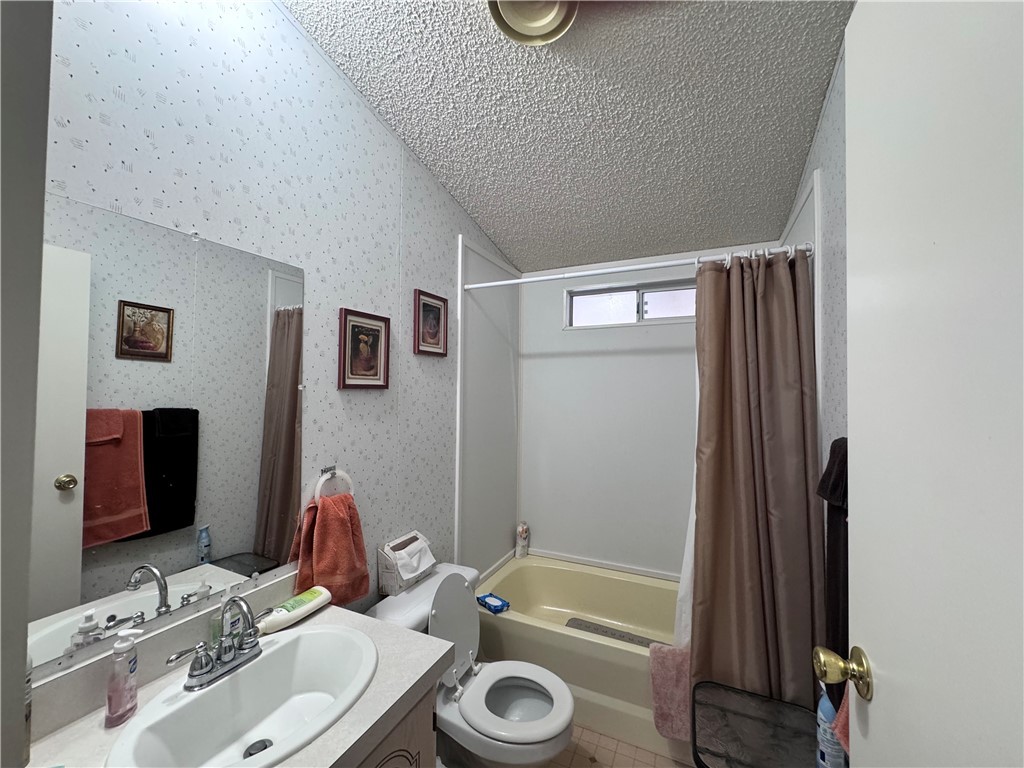 2532 Morgan Road Fort Mohave, AZ 86426 - Photo 11 of 29 Full bath with shower / bath combo with shower curtain, vanity, wallpapered walls, and a textured ceiling