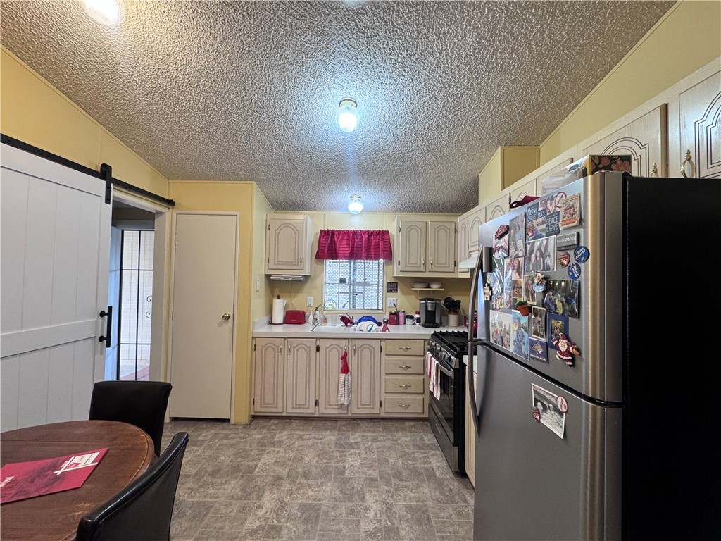 2532 Morgan Road Fort Mohave, AZ 86426 - Photo 14 of 29 Kitchen with stainless steel appliances, a barn door, light countertops, a textured ceiling, and stone finish floors