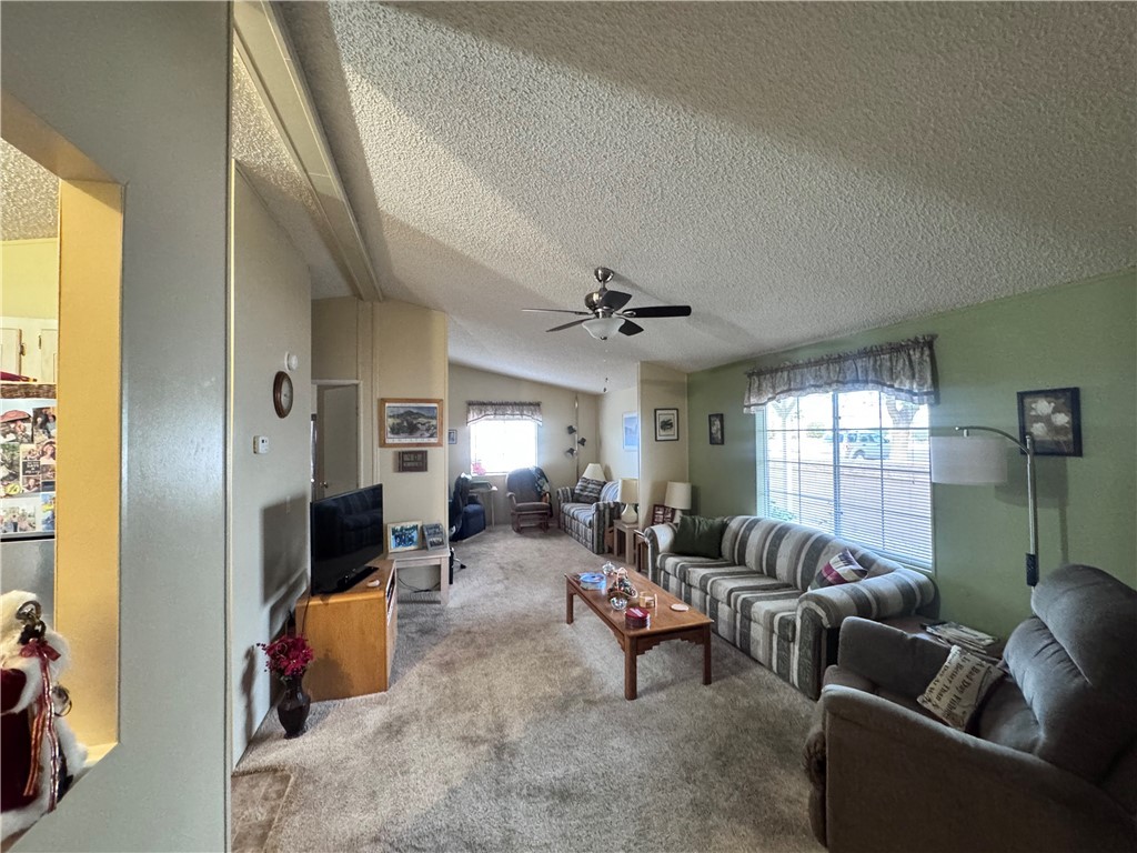 2532 Morgan Road Fort Mohave, AZ 86426 - Photo 7 of 29 Carpeted living room with lofted ceiling, ceiling fan, and a textured ceiling
