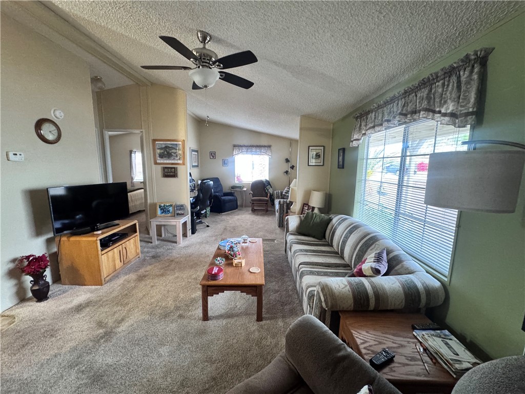 2532 Morgan Road Fort Mohave, AZ 86426 - Photo 8 of 29 Living area featuring carpet flooring, vaulted ceiling, a textured ceiling, and ceiling fan
