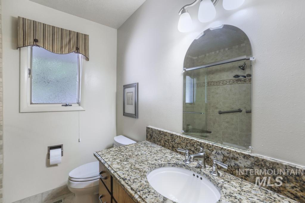 2018 Rancho Vista Drive Twin Falls, ID 83301 - Photo 26 of 50 Bathroom vanity featuring a granite countertop with an undermount sink, brushed nickel faucet, and wood-finish cabinetry