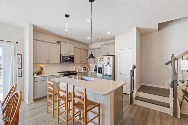 a kitchen with stainless steel appliances granite countertop a dining table chairs refrigerator and microwave