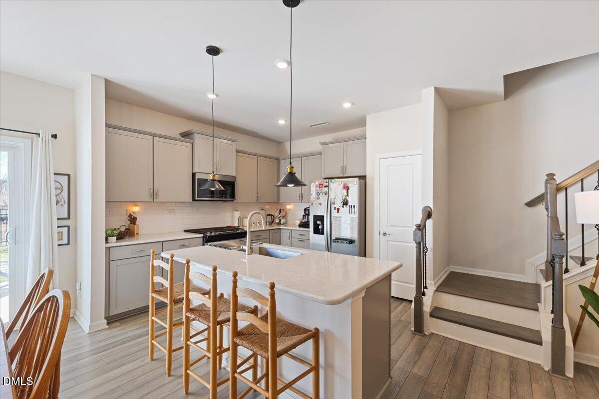 704 Colby Place Durham, NC 27713 - Photo 11 of 34 a kitchen with stainless steel appliances granite countertop a dining table chairs refrigerator and microwave