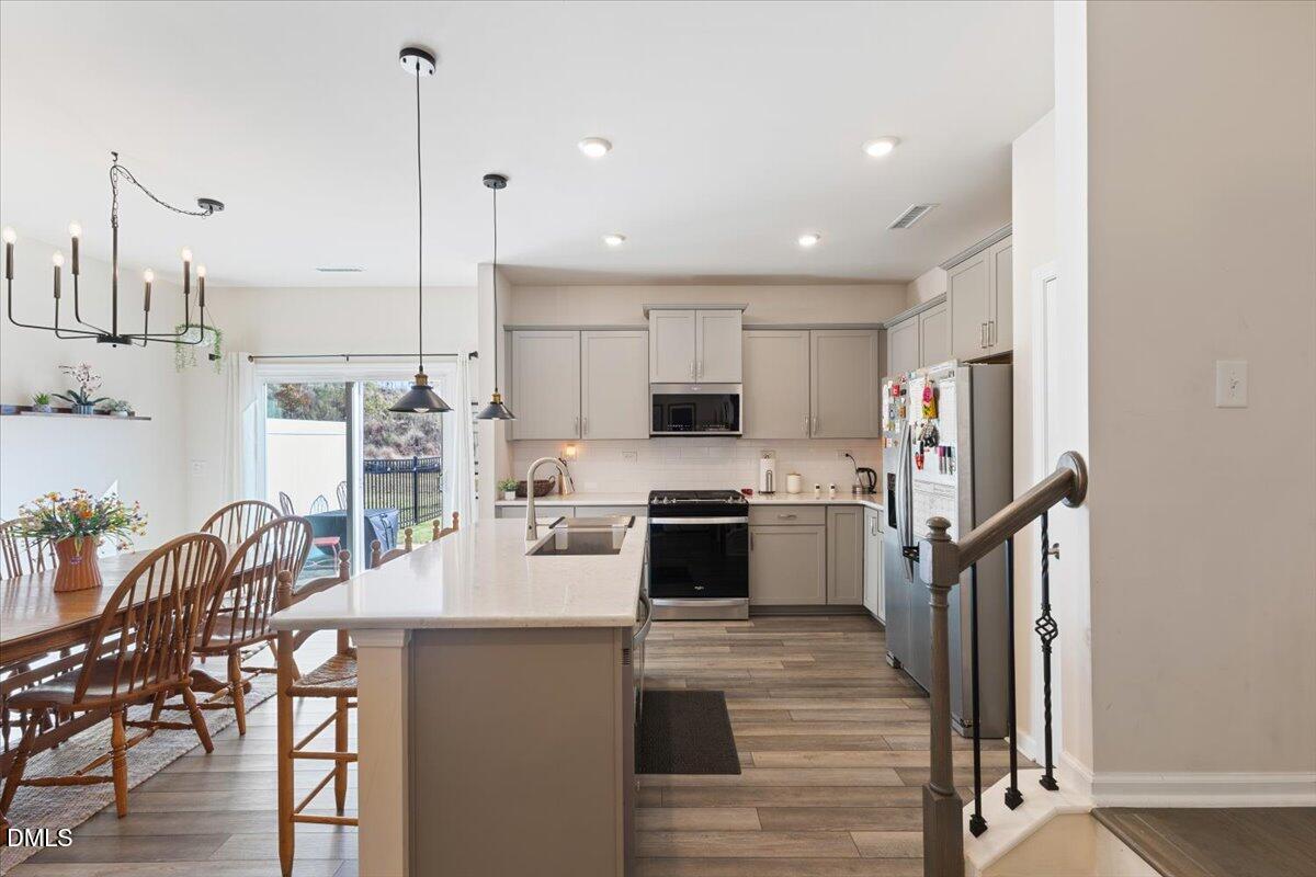 704 Colby Place Durham, NC 27713 - Photo 12 of 34 a kitchen with stainless steel appliances kitchen island granite countertop a refrigerator a stove a sink dishwasher with a dining table and chairs with wooden floor