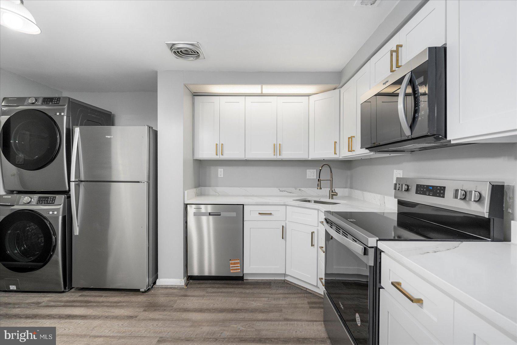 6317 Park Heights Avenue, Unit 616 Baltimore, MD 21215 - Photo 13 of 36 a kitchen with stainless steel appliances granite countertop a sink a stove a washer and dryer