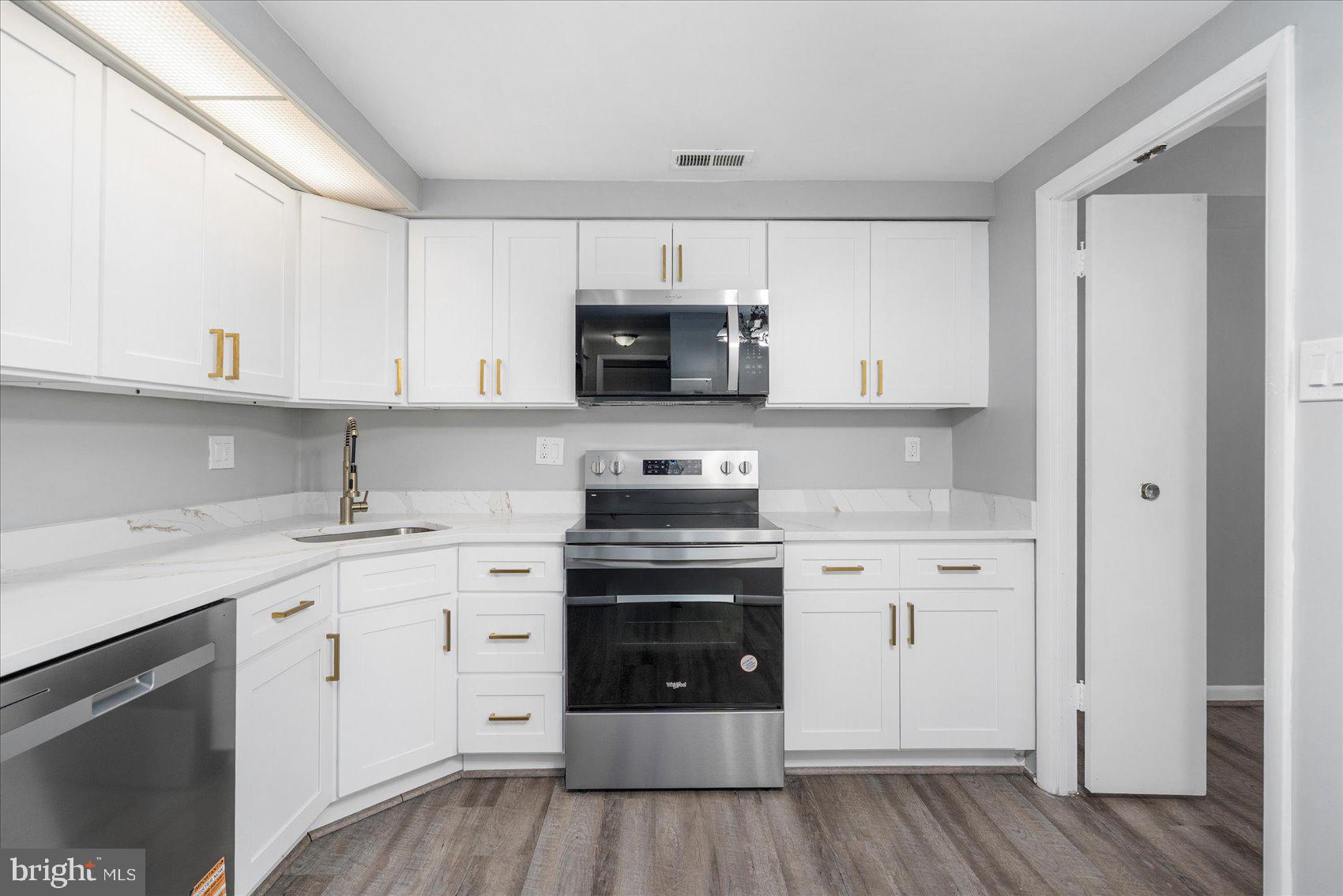 6317 Park Heights Avenue, Unit 616 Baltimore, MD 21215 - Photo 17 of 36 a kitchen with stainless steel appliances granite countertop a stove and white cabinets