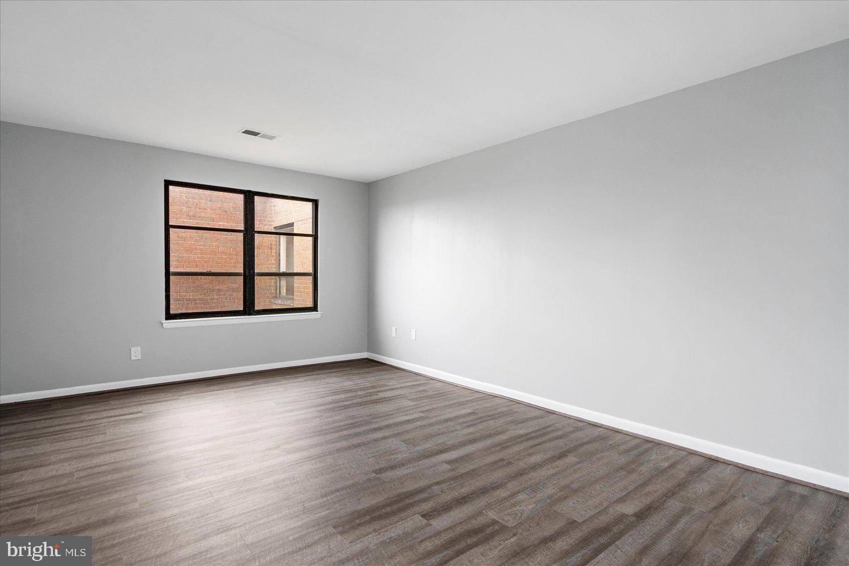 6317 Park Heights Avenue, Unit 616 Baltimore, MD 21215 - Photo 24 of 36 an empty room with wooden floor and windows