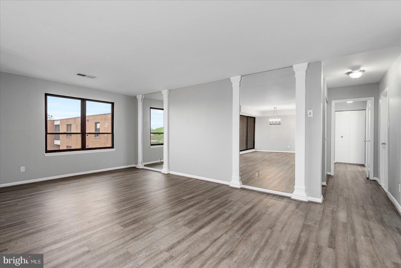 6317 Park Heights Avenue, Unit 616 Baltimore, MD 21215 - Photo 9 of 36 an empty room with wooden floor and windows