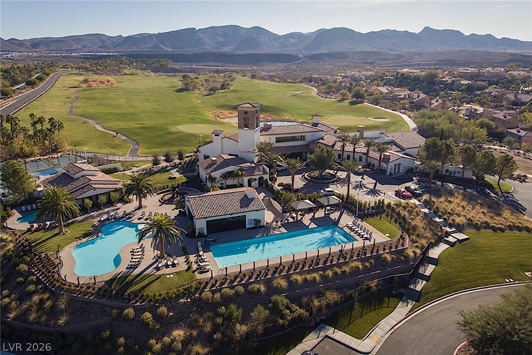 25 Falling Ridge Lane Henderson, NV 89011 - Photo 35 of 48 An aerial perspective reveals a luxurious community hub with sparkling pools and a meticulously maintained golf course against a mountain backdrop.