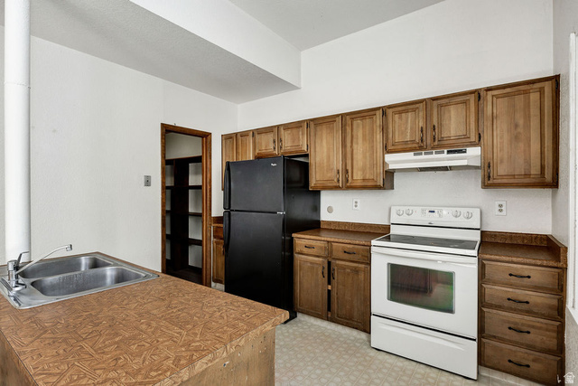 299 West Center Street, Unit 2 Logan, UT 84321 - Photo 11 of 46 Kitchen featuring a double basin stainless steel sink, wood-finish countertops, black refrigerator, white electric range, and wood cabinetry with dark hardware