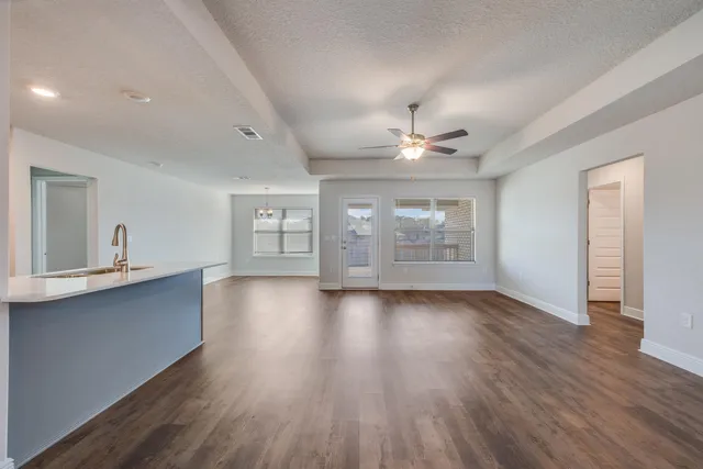 a view of an empty room with window and wooden floor