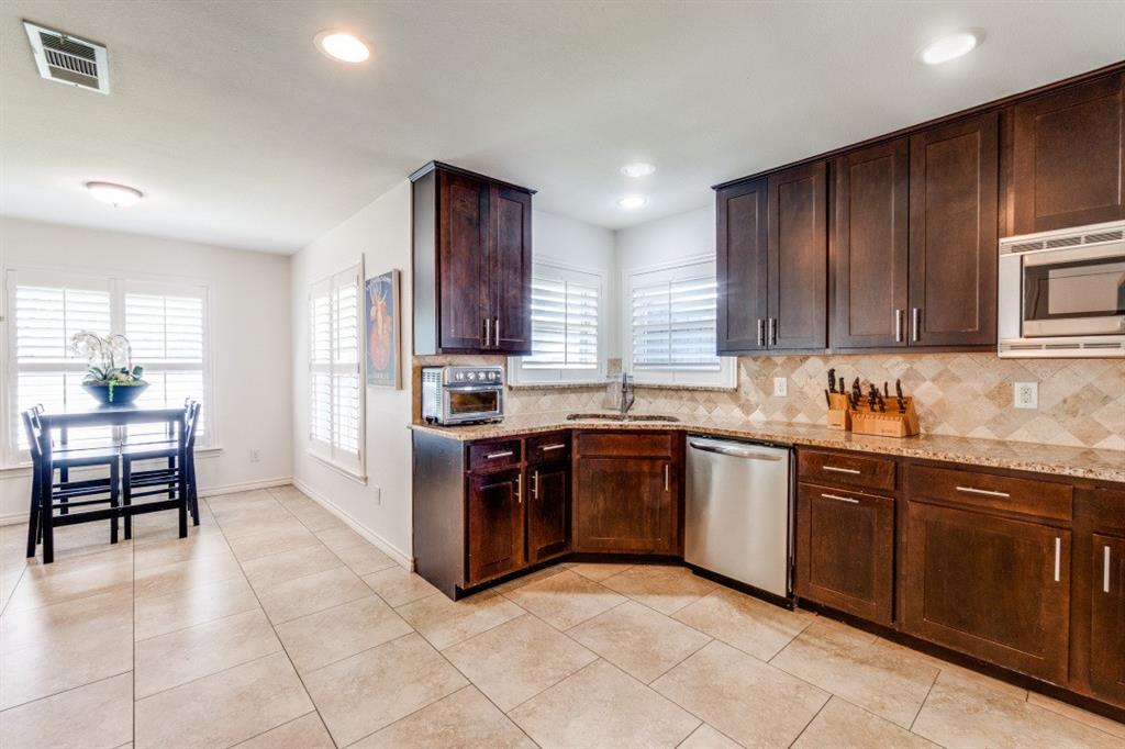 4303 Skillman Street Dallas, TX 75206 - Photo 10 of 25 a kitchen with stainless steel appliances granite countertop a stove top oven a sink dishwasher and a refrigerator