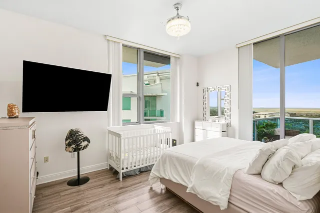 a bedroom with a bed television and a large window