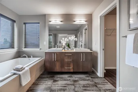 a bathroom with a tub a double vanity sink a mirror a window and a shower