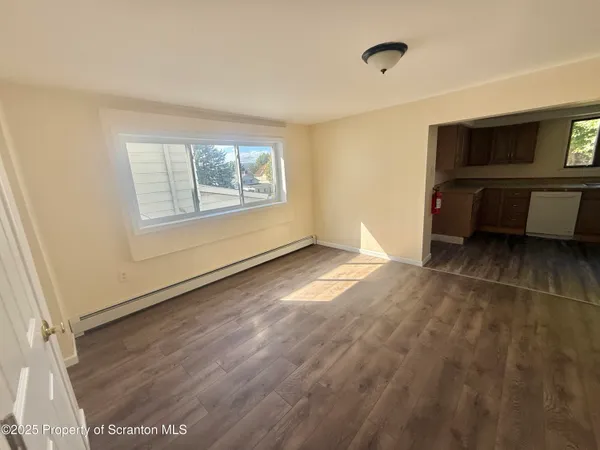 a view of an empty room with a window and a kitchen