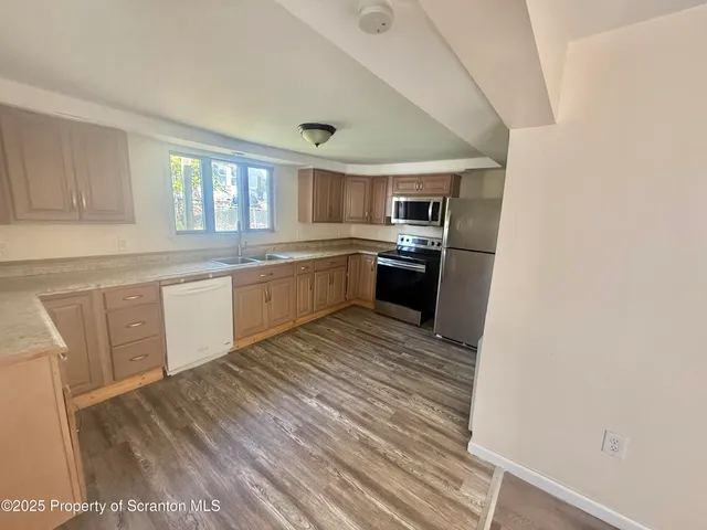 a large kitchen with wooden floor and stainless steel appliances