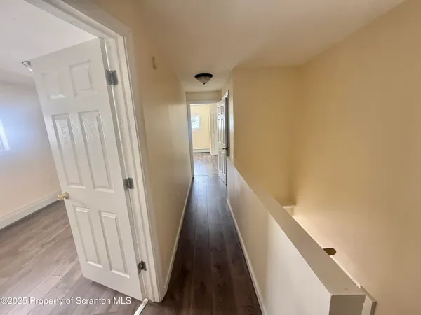 a view of a hallway with wooden floor and staircase