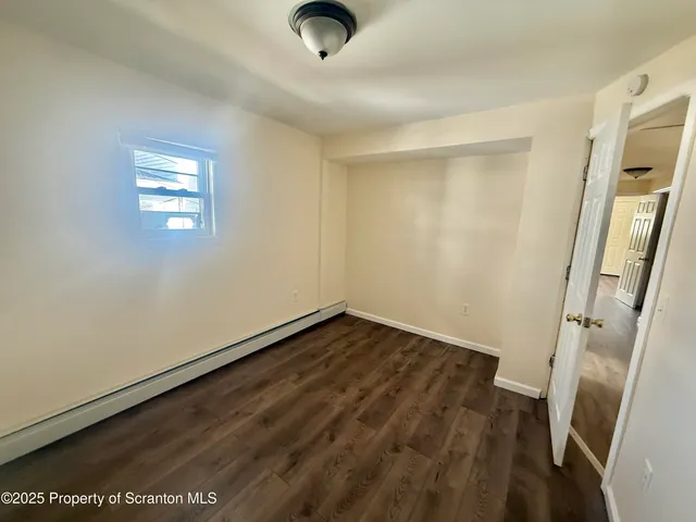 an empty room with wooden floor and window