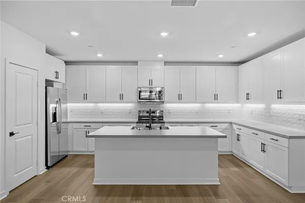 a view of a kitchen with stainless steel appliances granite countertop a stove a sink and a refrigerator