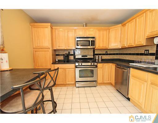 19 New Road Kendall Park, NJ 08824 - Photo 11 of 21 a kitchen with stainless steel appliances a stove a sink and white cabinets