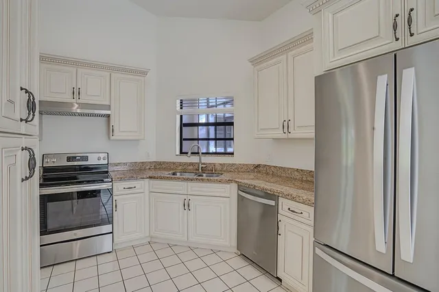 a kitchen with white cabinets a sink and appliances