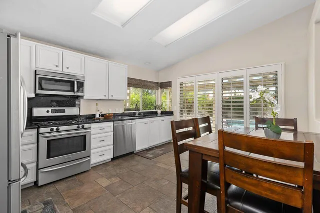 a open kitchen with stainless steel appliances granite countertop a stove a sink and a microwave