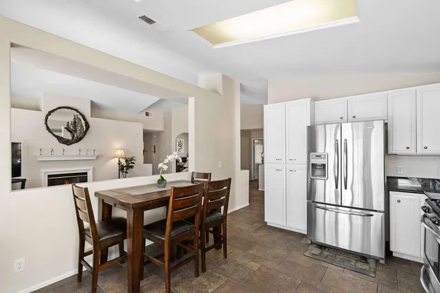 a kitchen with stainless steel appliances a refrigerator a stove a dining table and chairs