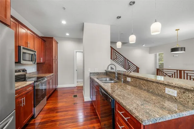 a large kitchen with granite countertop a sink and dishwasher with wooden floor