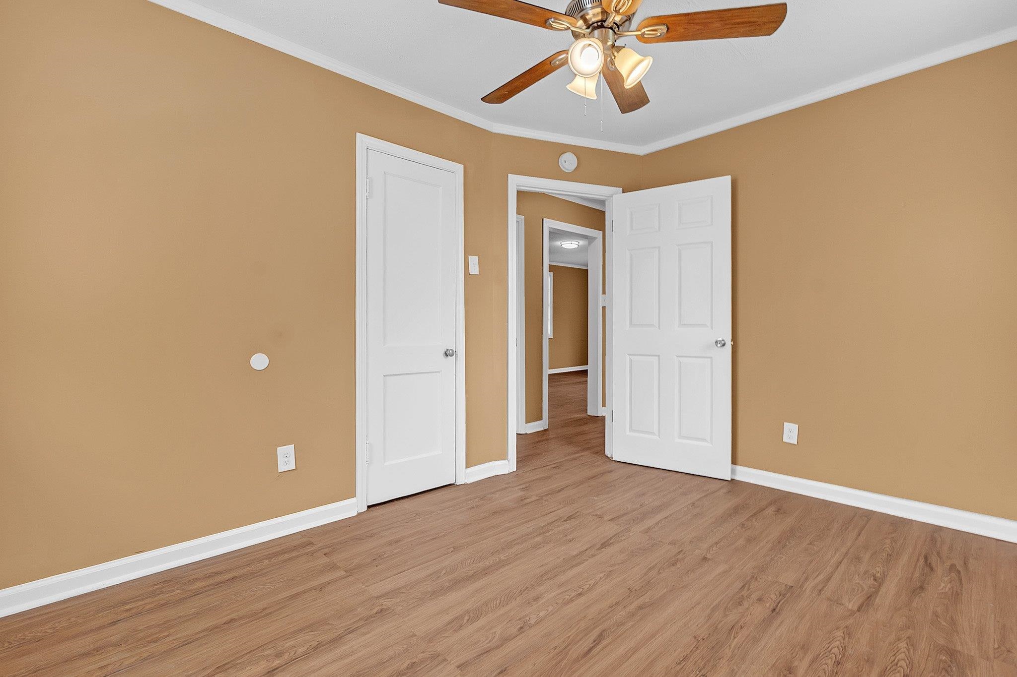3186 Alta Road Memphis, TN 38109 - Photo 11 of 14 Room featuring wood-finish flooring, neutral wall tones, white trim, a ceiling fan with integrated lighting, and multiple paneled doors