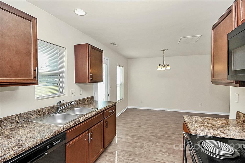 8729 Pence Road Charlotte, NC 28215 - Photo 11 of 26 a kitchen with stainless steel appliances granite countertop a sink stove and cabinets