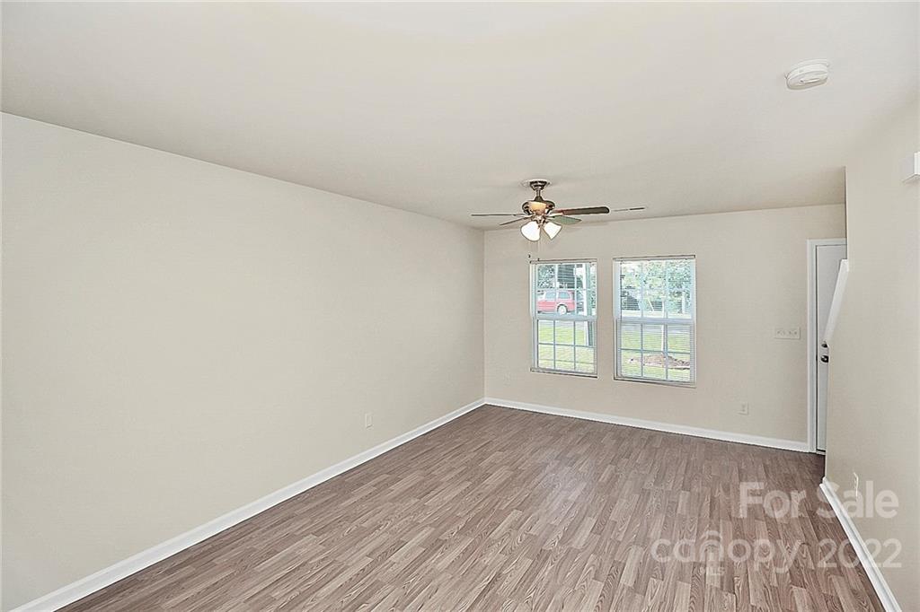 8729 Pence Road Charlotte, NC 28215 - Photo 4 of 26 an empty room with wooden floor chandelier fan and windows
