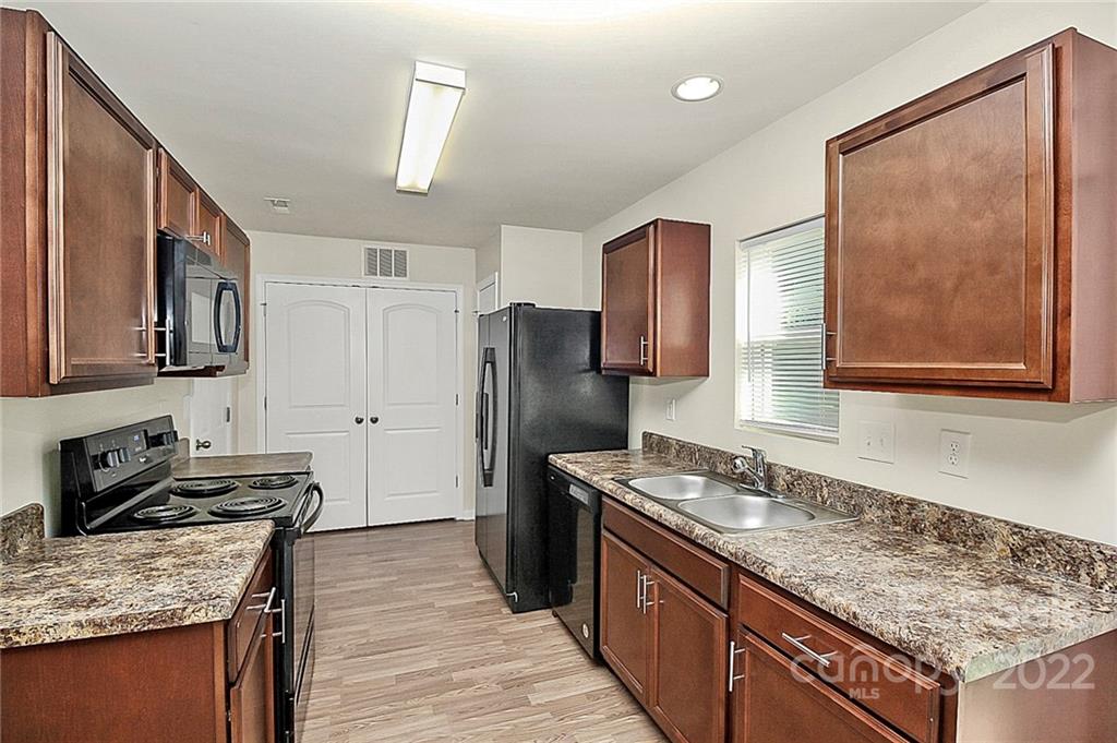 8729 Pence Road Charlotte, NC 28215 - Photo 9 of 26 a kitchen with granite countertop a sink stove and refrigerator