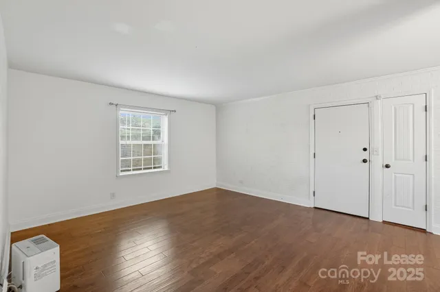 a view of a kitchen with refrigerator and wooden floor