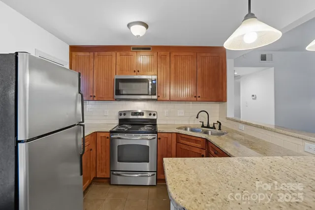 a kitchen with stainless steel appliances granite countertop a refrigerator a sink a stove and island