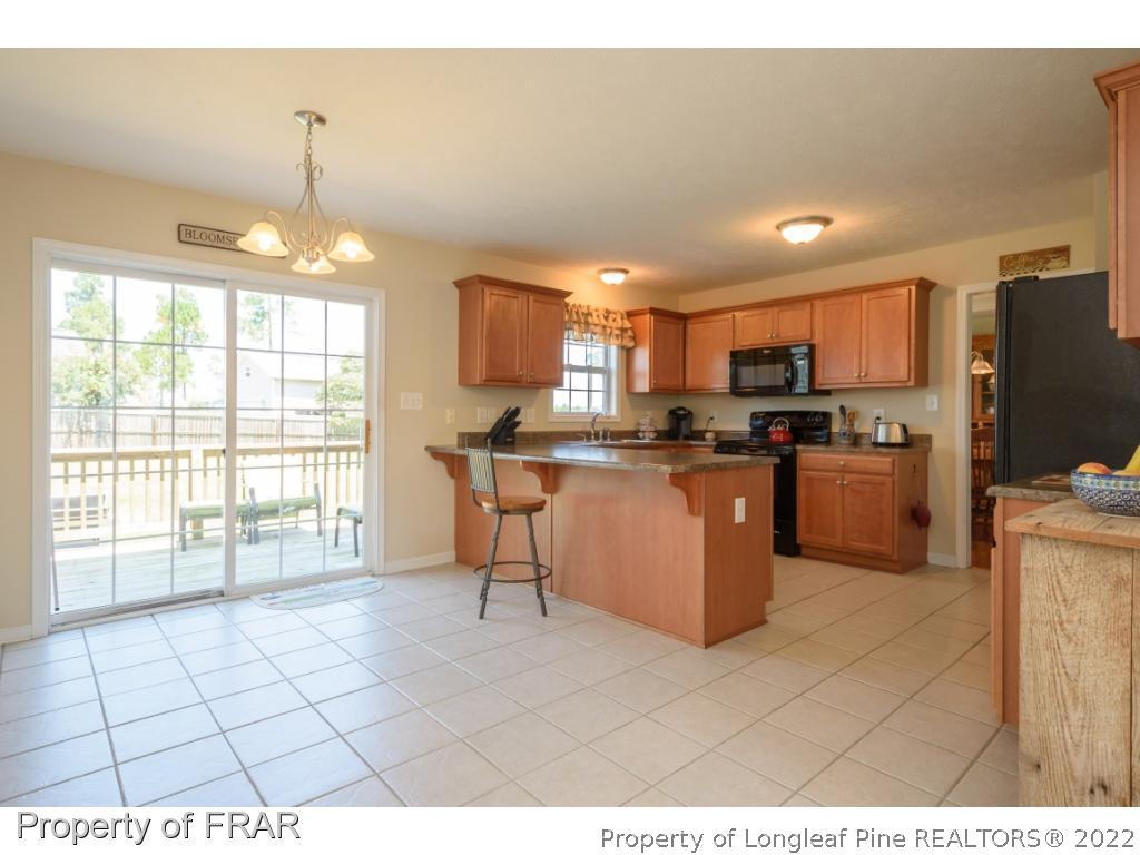11 Lattimore Road Cameron, NC 28326 - Photo 8 of 28 a kitchen with stainless steel appliances a microwave a stove a refrigerator a sink dishwasher with a dining table and chairs