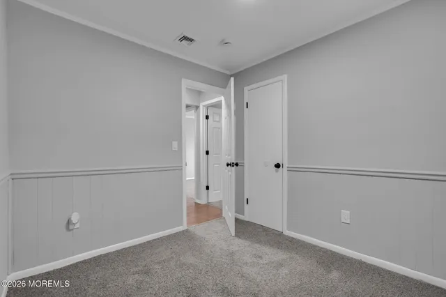 a front view of a house with a dirt yard and a large tree