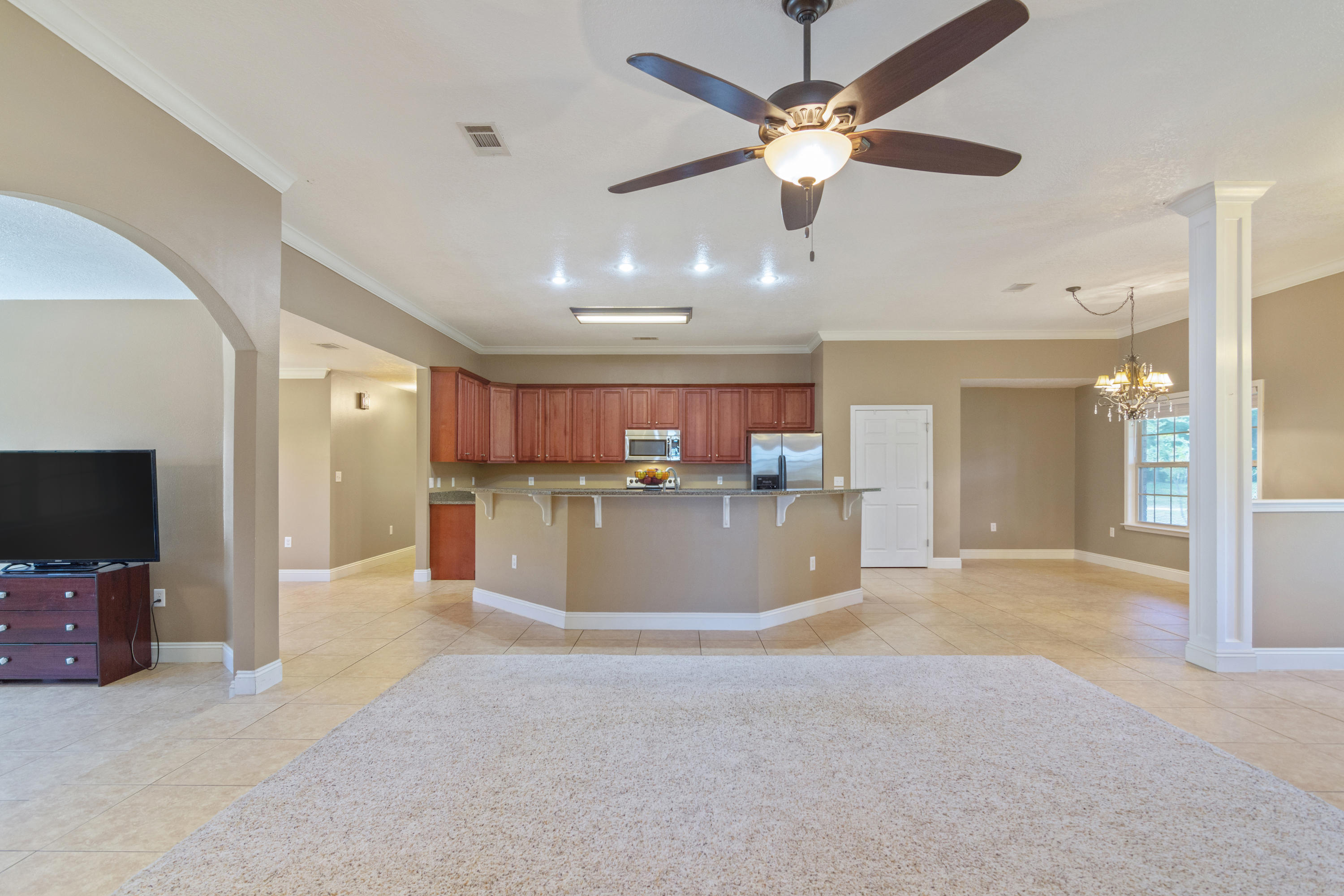 6589 Old River Road Baker, FL 32531 - Photo 14 of 49 a view of a livingroom with a flat screen tv a ceiling fan and a kitchen
