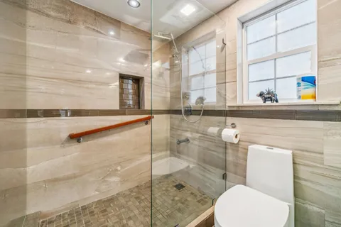 a bathroom with a sink a toilet a mirror and shower