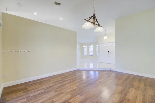 a view of an empty room with wooden floor and windows
