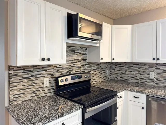a kitchen with granite countertop a sink stove and cabinets