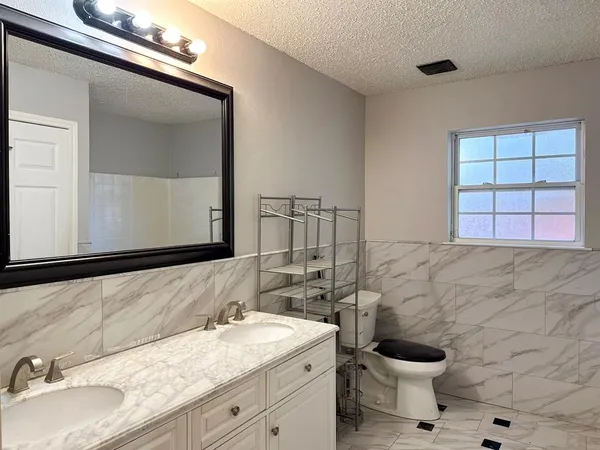 a bathroom with a granite countertop sink toilet a mirror and shower