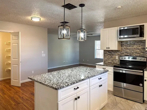 a kitchen with granite countertop a stove cabinets and wooden floor