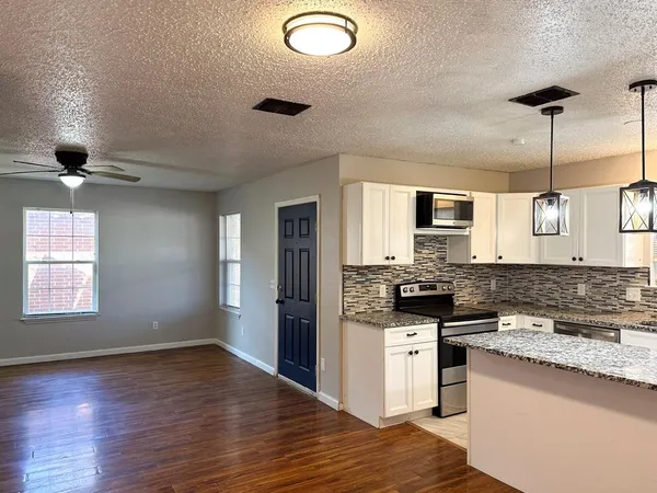 a kitchen with granite countertop a sink a counter top space and cabinets