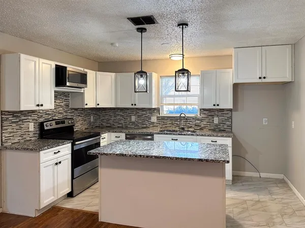 a kitchen with granite countertop a sink stove and cabinets
