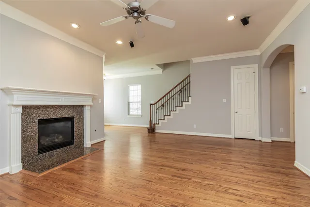 a view of an empty room with wooden floor fireplace and a window