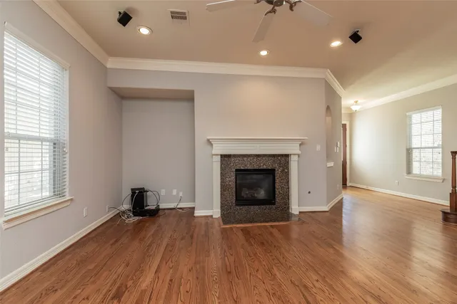 an empty room with wooden floor a fireplace and windows